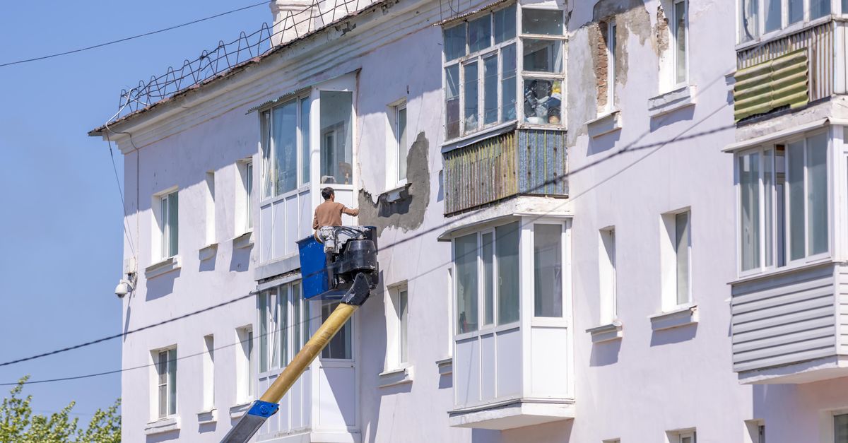 Schilder werkt vanaf een hoogwerker aan de gevel van een gebouw