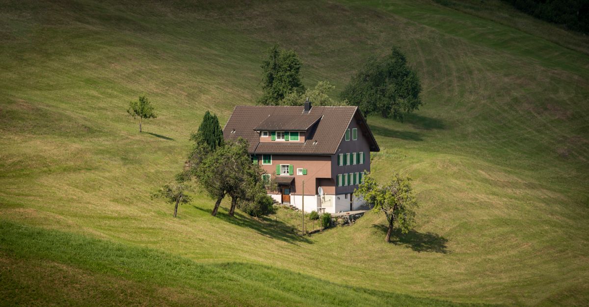 Vrijstaand huis tussen bomen op een groene heuvel