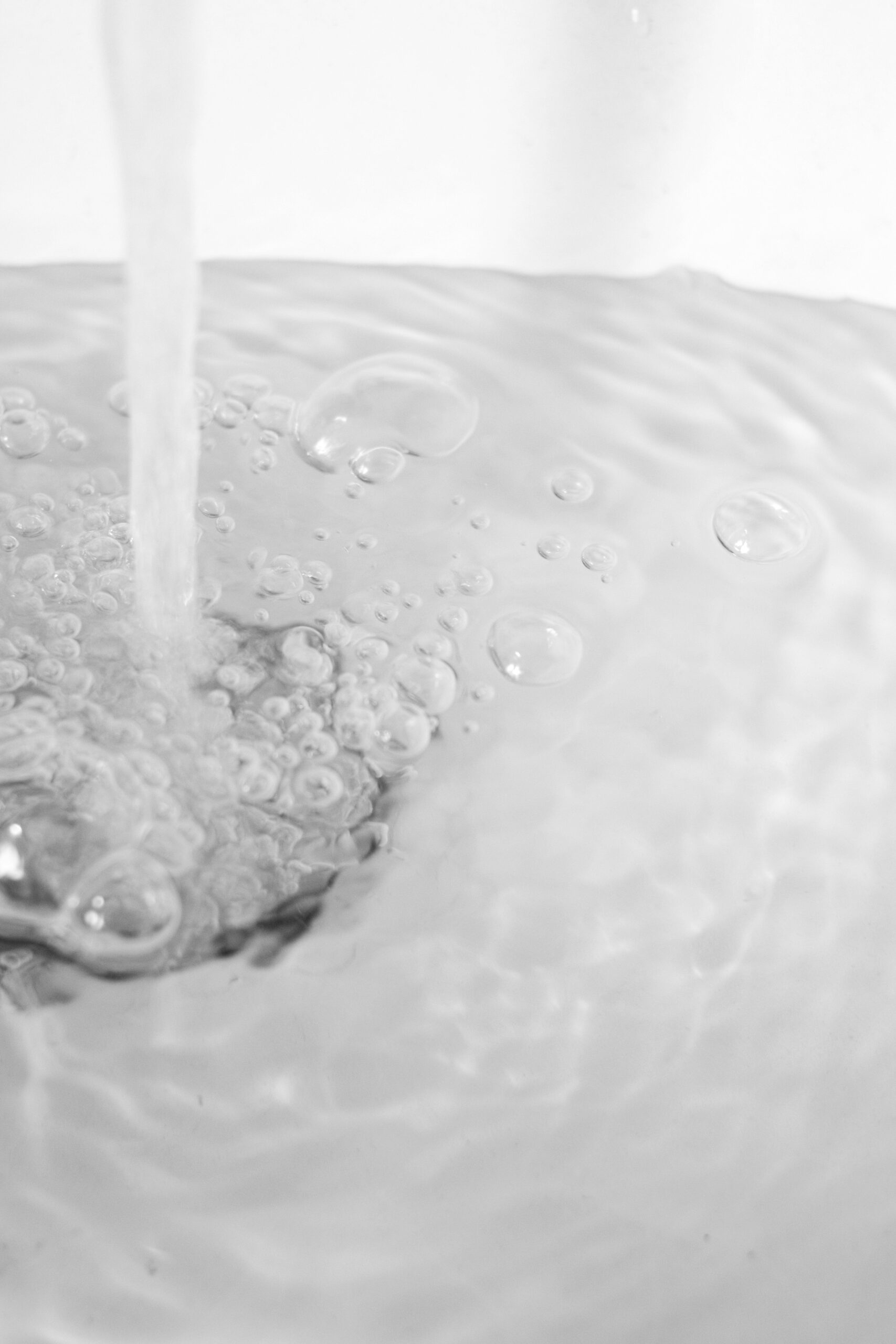 Close-up van water met bubbels dat in een gootsteen stroomt